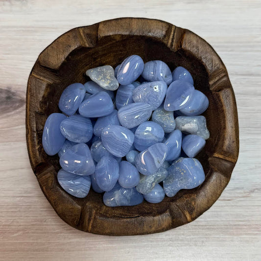 Wooden bowl filled with blue stones on a light wooden surface