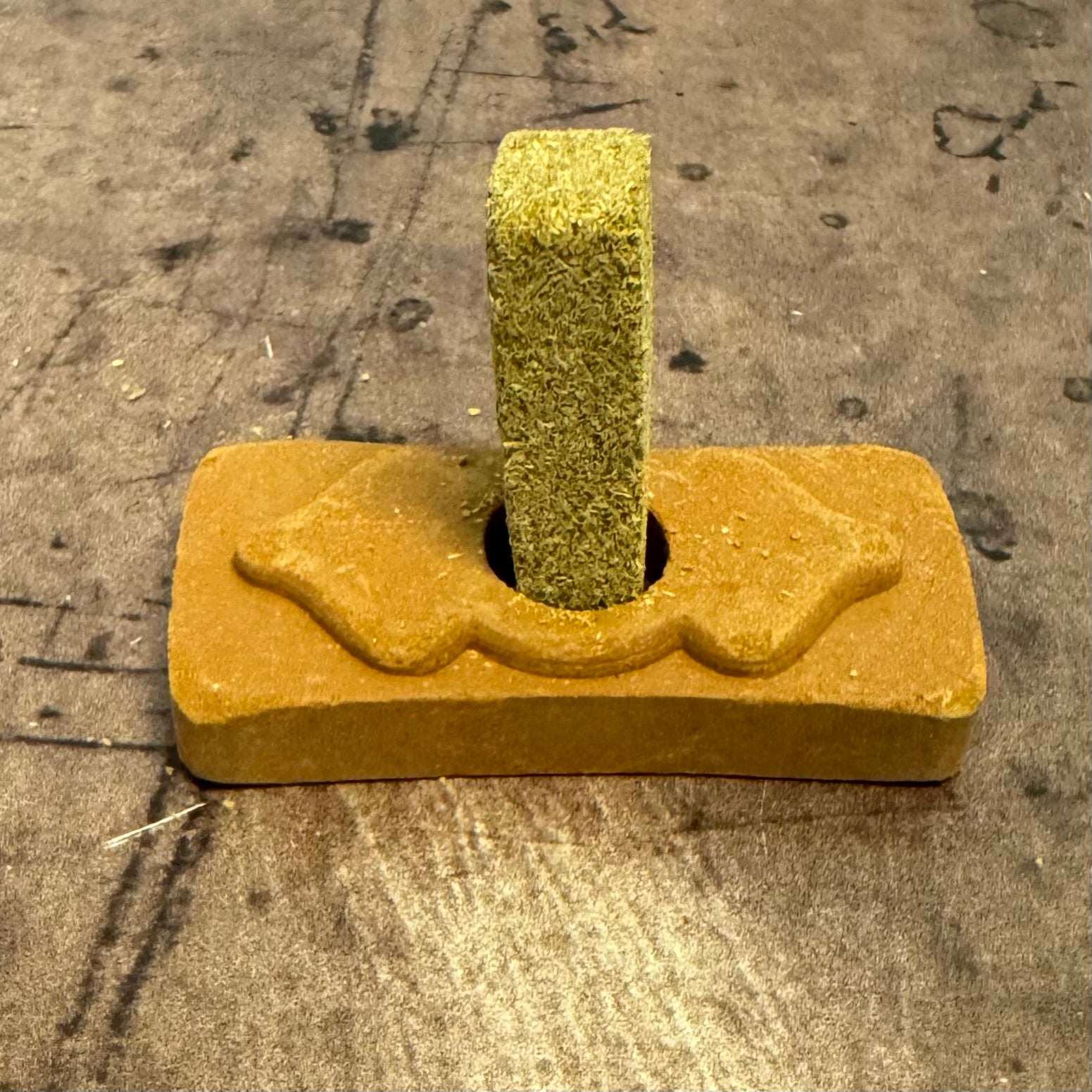 Yellow dog chew toy with a central green textured piece on a concrete surface
