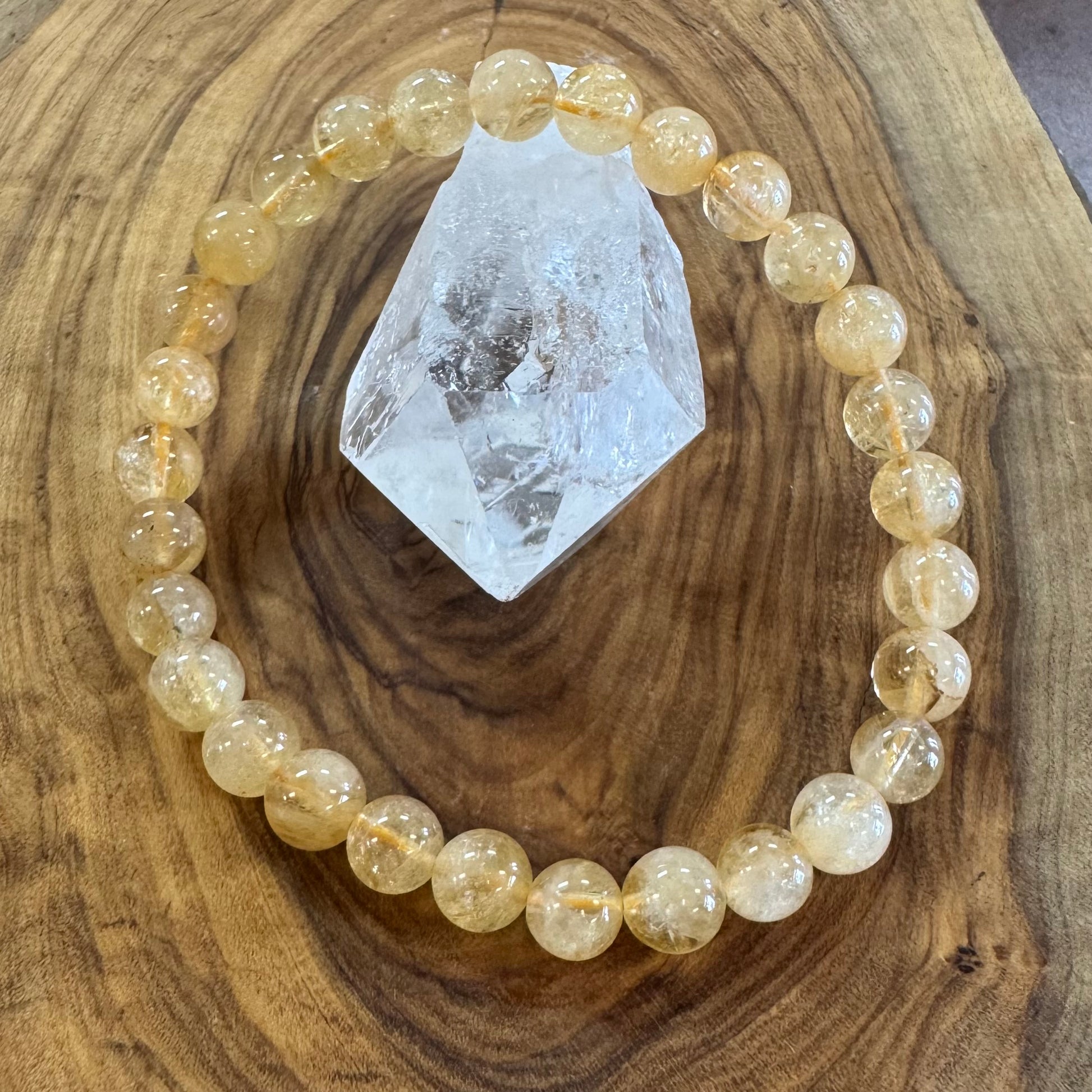 Beaded bracelet with yellow stones on a wooden surface with a crystal