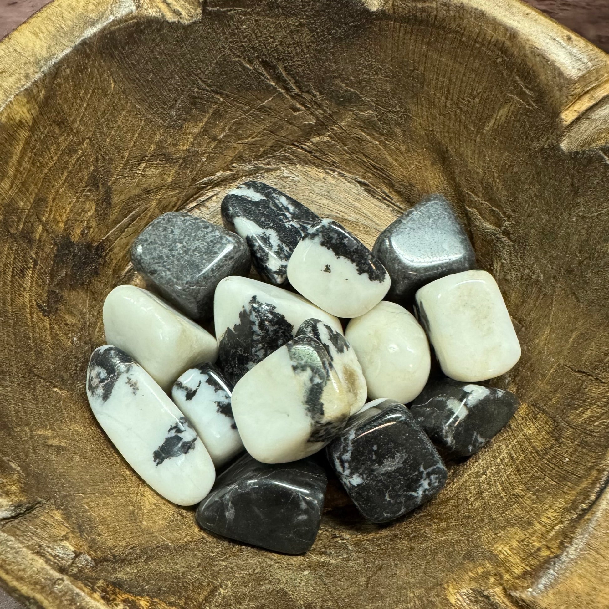 Collection of black and white stones in a wooden bowl