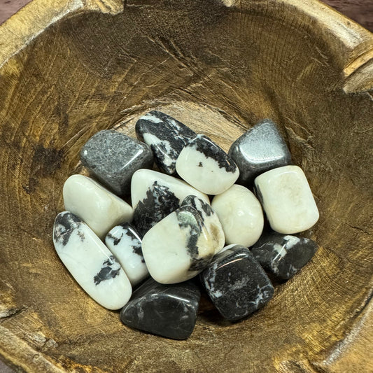 Collection of black and white stones in a wooden bowl