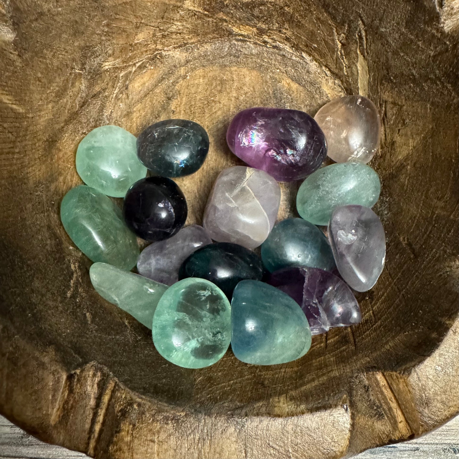 Assorted colorful crystals in a wooden bowl