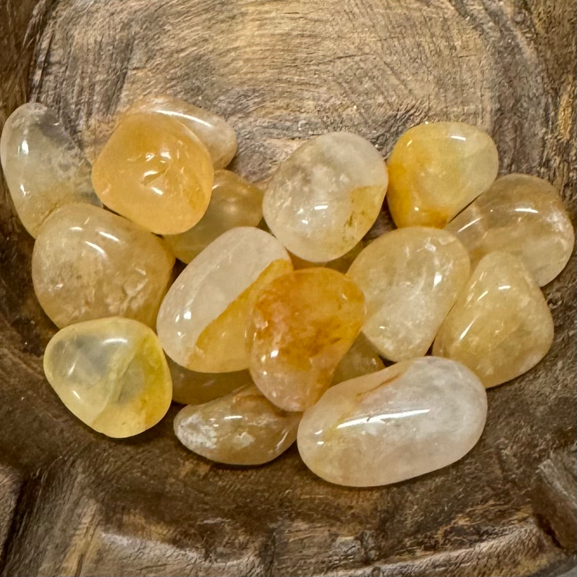 Collection of polished yellow and beige stones on a wooden surface.