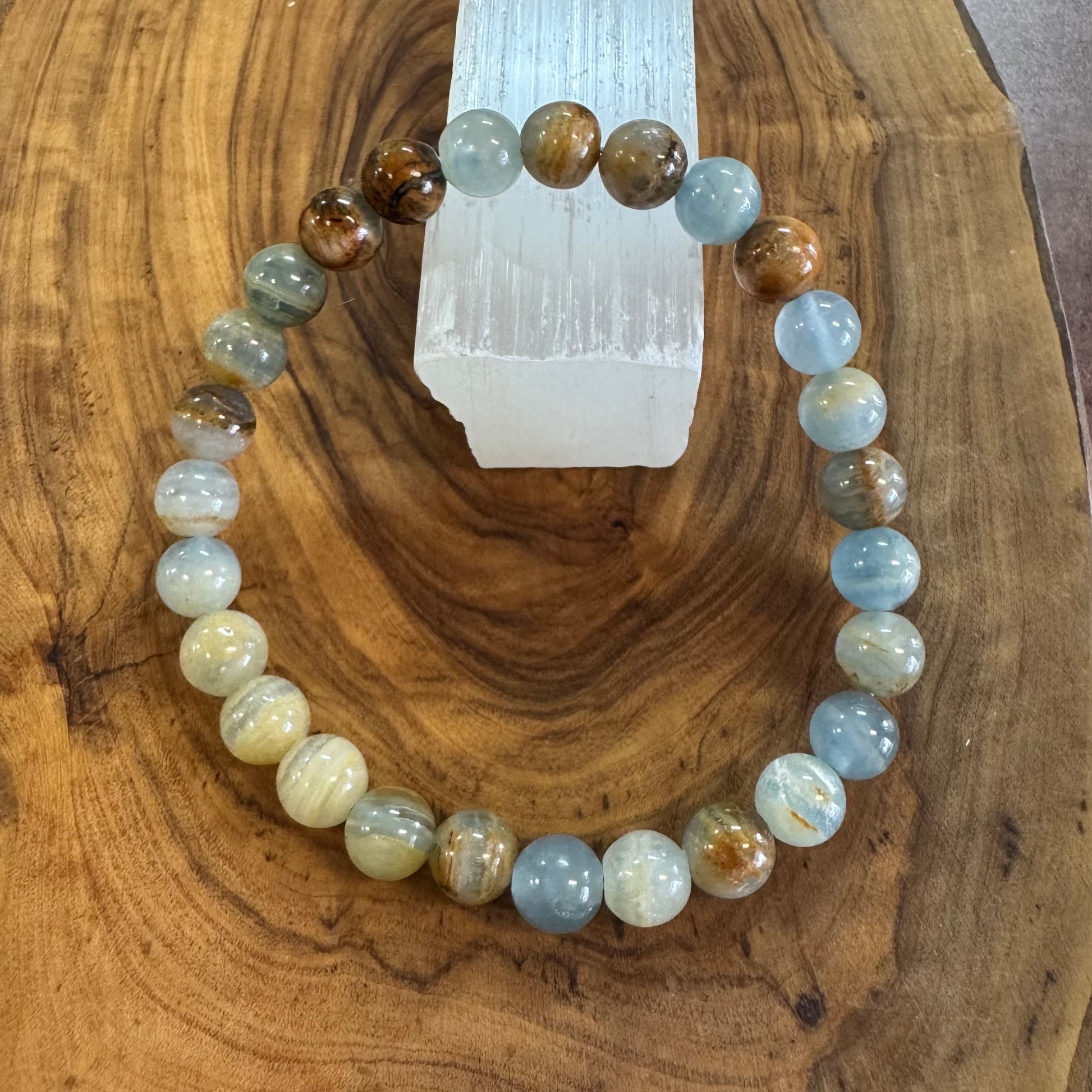 Beaded bracelet on a wooden surface with a crystal in the background