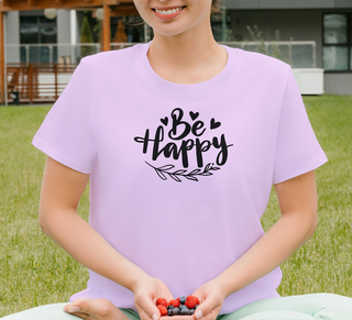 Heather Prism Lilac Be Happy t-shirt with hand-lettered script, hearts, and a leaf design, worn sitting outdoors