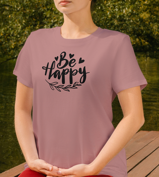 Mauve Be Happy t-shirt with hand-lettered script, hearts, and a leaf design, worn outdoors