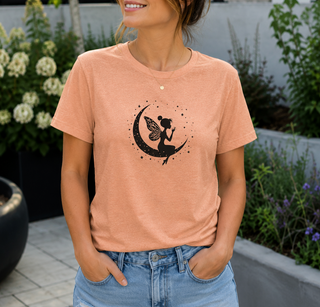 Heather Peach Fairy on Crescent Moon t-shirt with a black fairy and stars design, worn outdoors