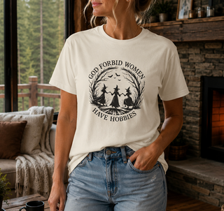White God Forbid Women Have Hobbies t-shirt with a vintage moonlit forest design of two women dancing, worn in a cozy indoor setting