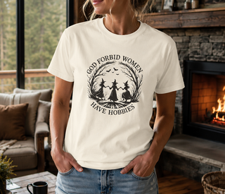White God Forbid Women Have Hobbies t-shirt with a vintage moonlit forest design of two women dancing, worn in a cozy indoor setting