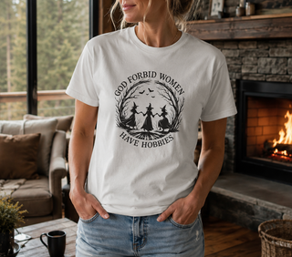 White God Forbid Women Have Hobbies t-shirt with a vintage moonlit forest design of two women dancing, worn in a cozy living room