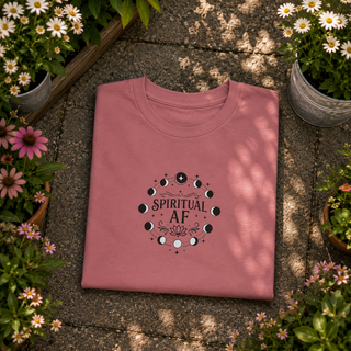 Folded Mauve Spiritual AF moon phase tee on a stone surface with flowers