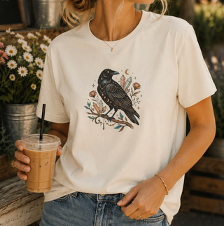 Crow Moon tee featuring a hand-drawn crow with crescent moons and florals, worn by a model