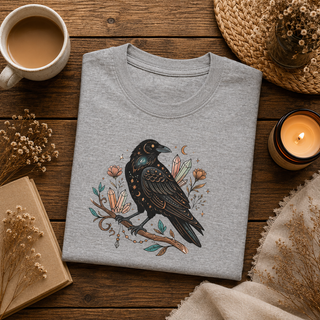 Folded Crow Moon tee featuring a hand-drawn crow with crescent moons and florals, styled in a flatlay