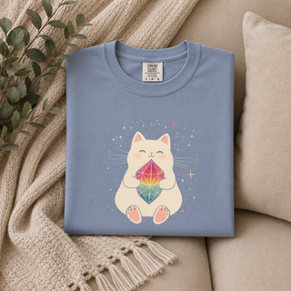 Folded Blue Jean Crystal Cat tee with a cute cat holding a rainbow gem on a beige couch