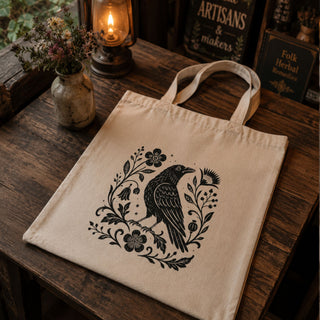 Folk Raven Tote in natural canvas — hand-illustrated raven with folk botanical florals in black linework