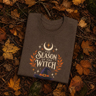 Heather brown unisex cotton tee printed with a witch hat, crescent moon, stars, and orange laurel leaves beneath 'The Season of the Witch' lettering.