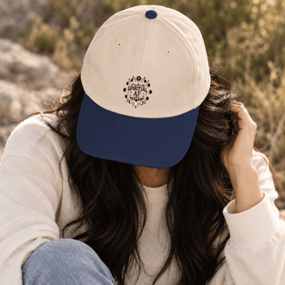 A person outdoors wearing a two-tone baseball cap with an off-white crown and a navy blue brim. The cap features a circular black graphic on the front with the text 'GOD IS A MAN' and 'JERUSALEM'.