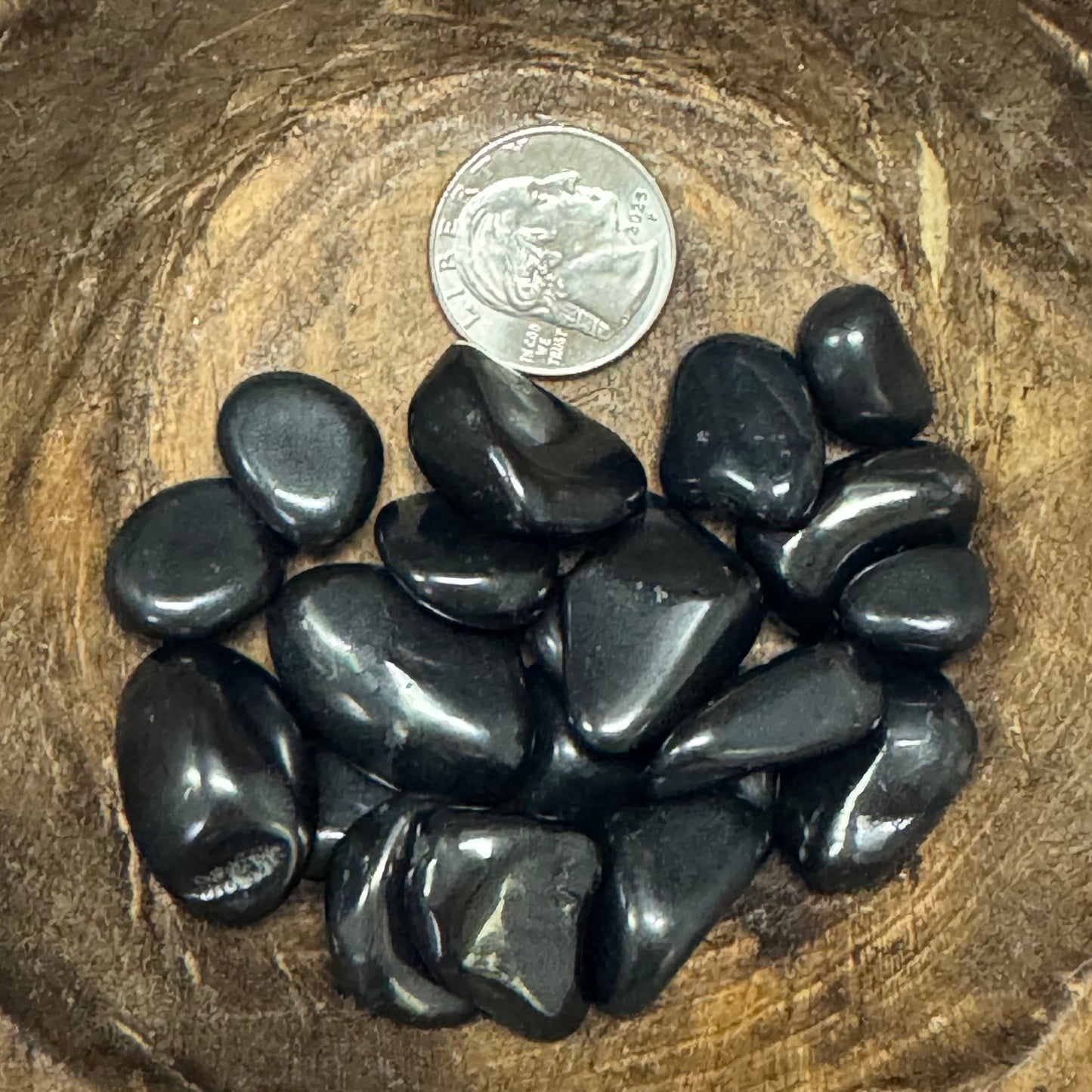 Black stones on a wooden surface with a coin for scale
