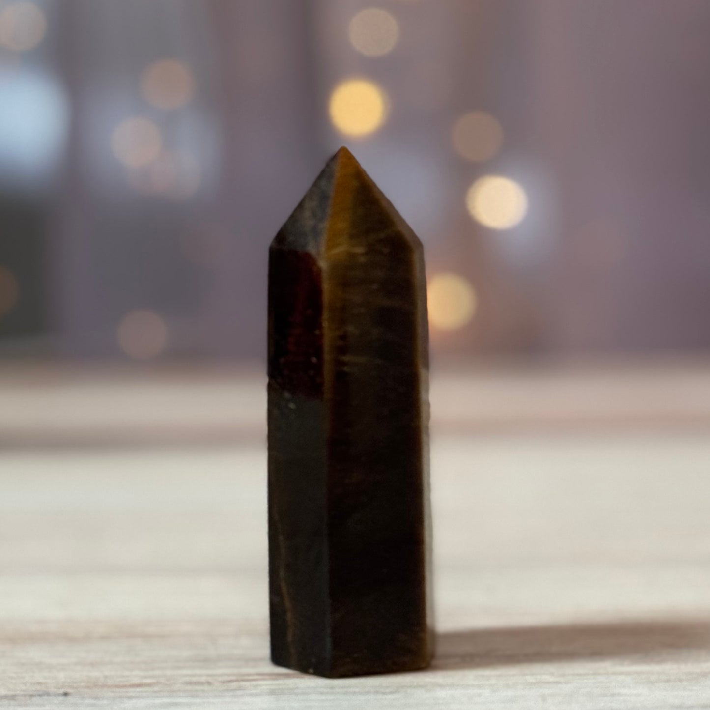 Black crystal pyramid on a wooden surface with a blurred background