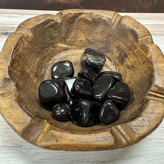 Wooden bowl with black stones on a wooden surface