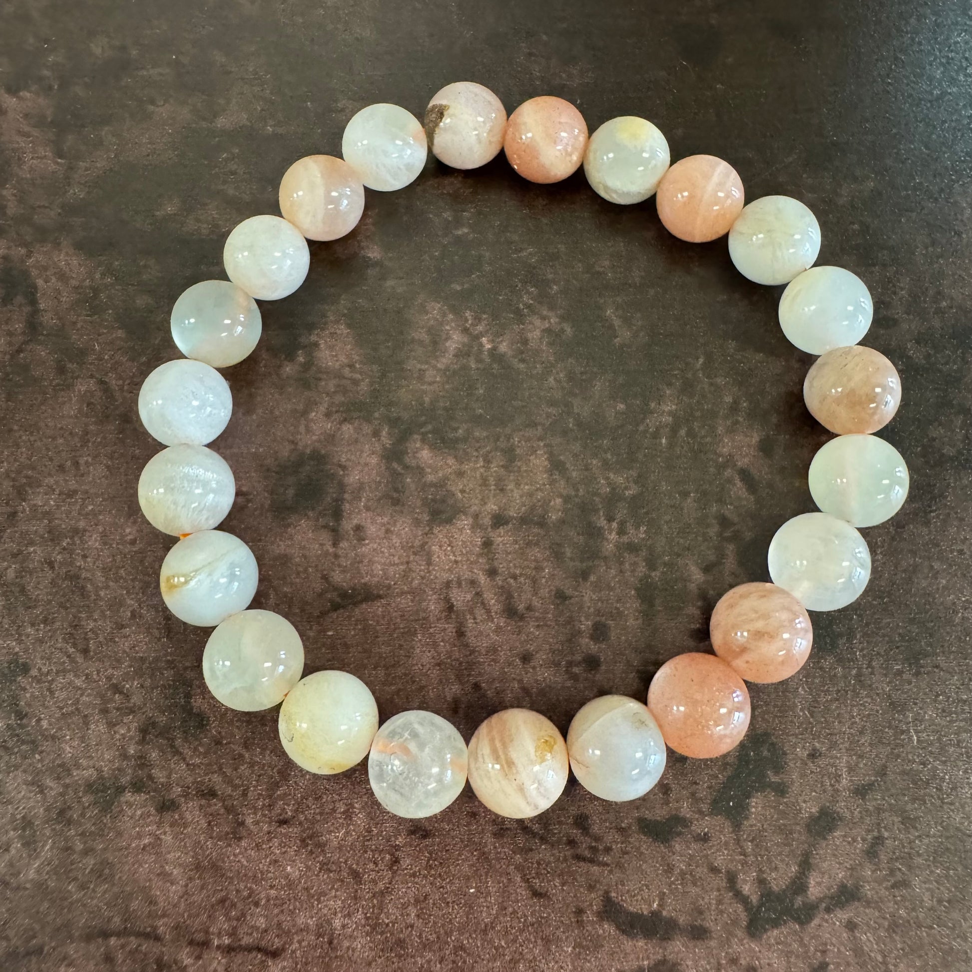 Round beaded bracelet with white and pink beads on a textured brown surface