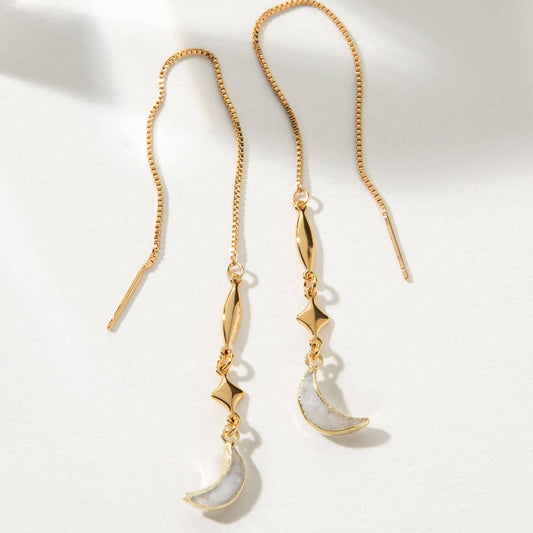 Gold and white earrings on a light background