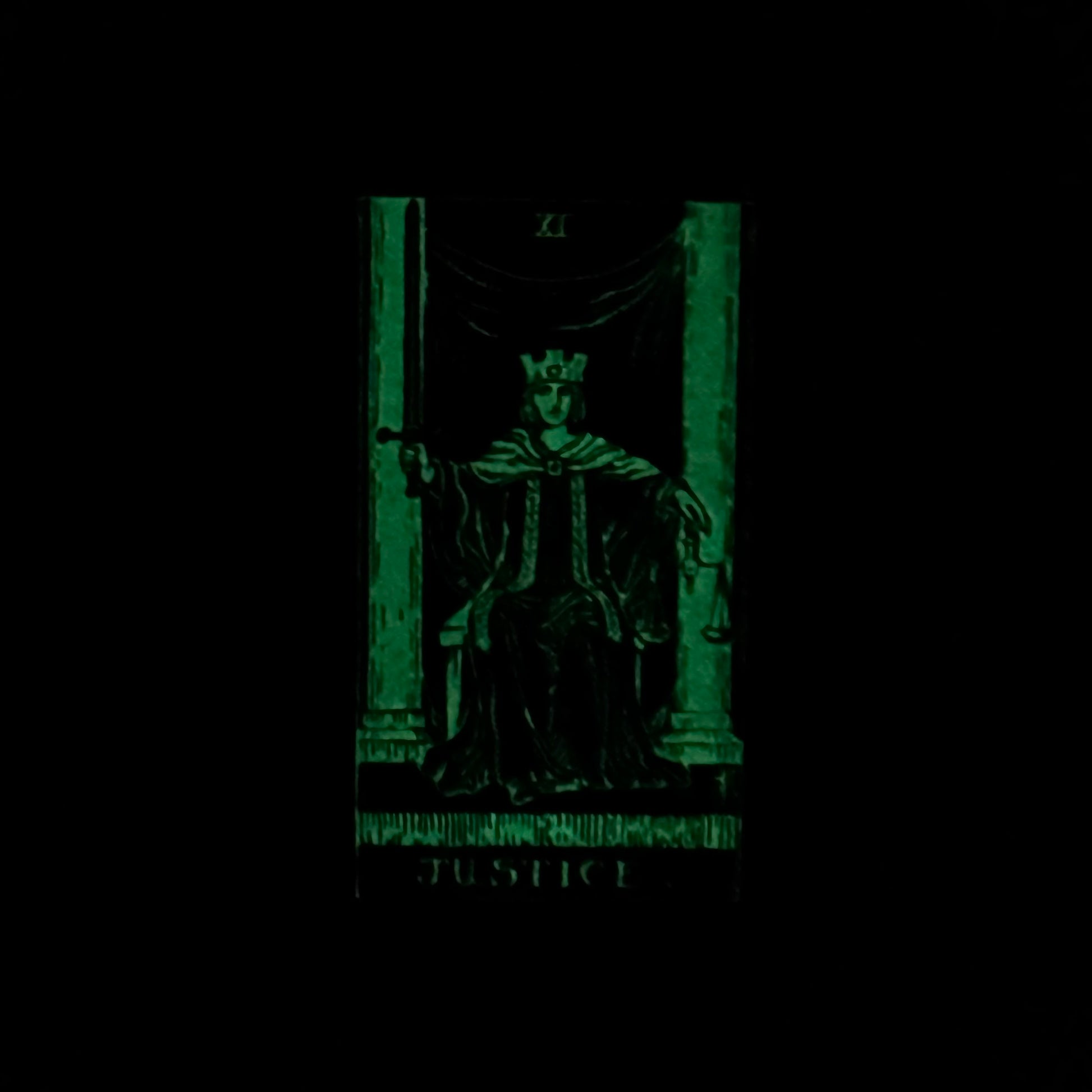 Tarot card featuring a figure named 'Justice' with a green glow on a black background