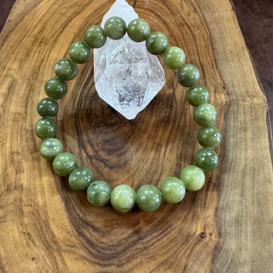 Green beaded bracelet on a wooden surface with a crystal