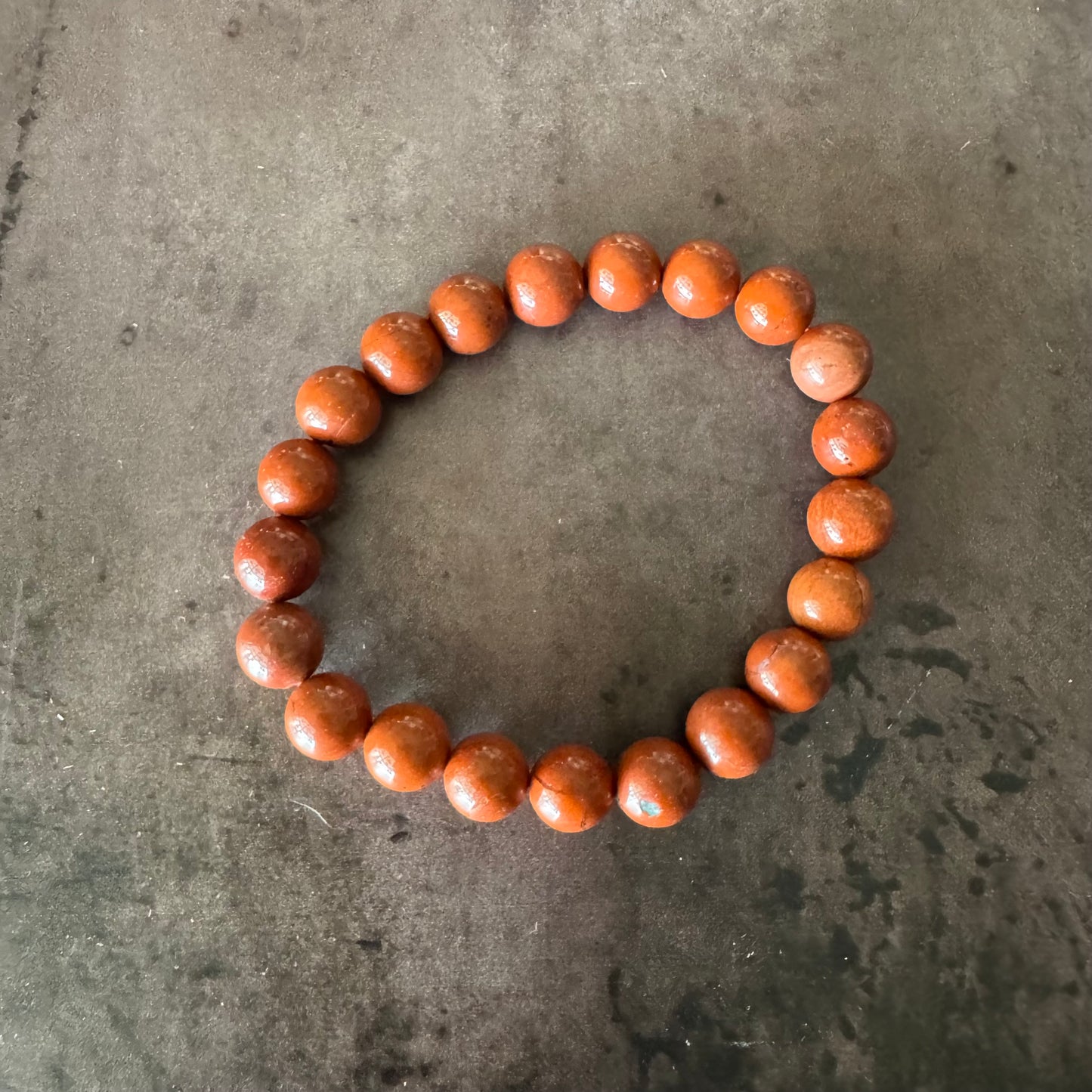Round bracelet made of brown beads on a gray concrete surface