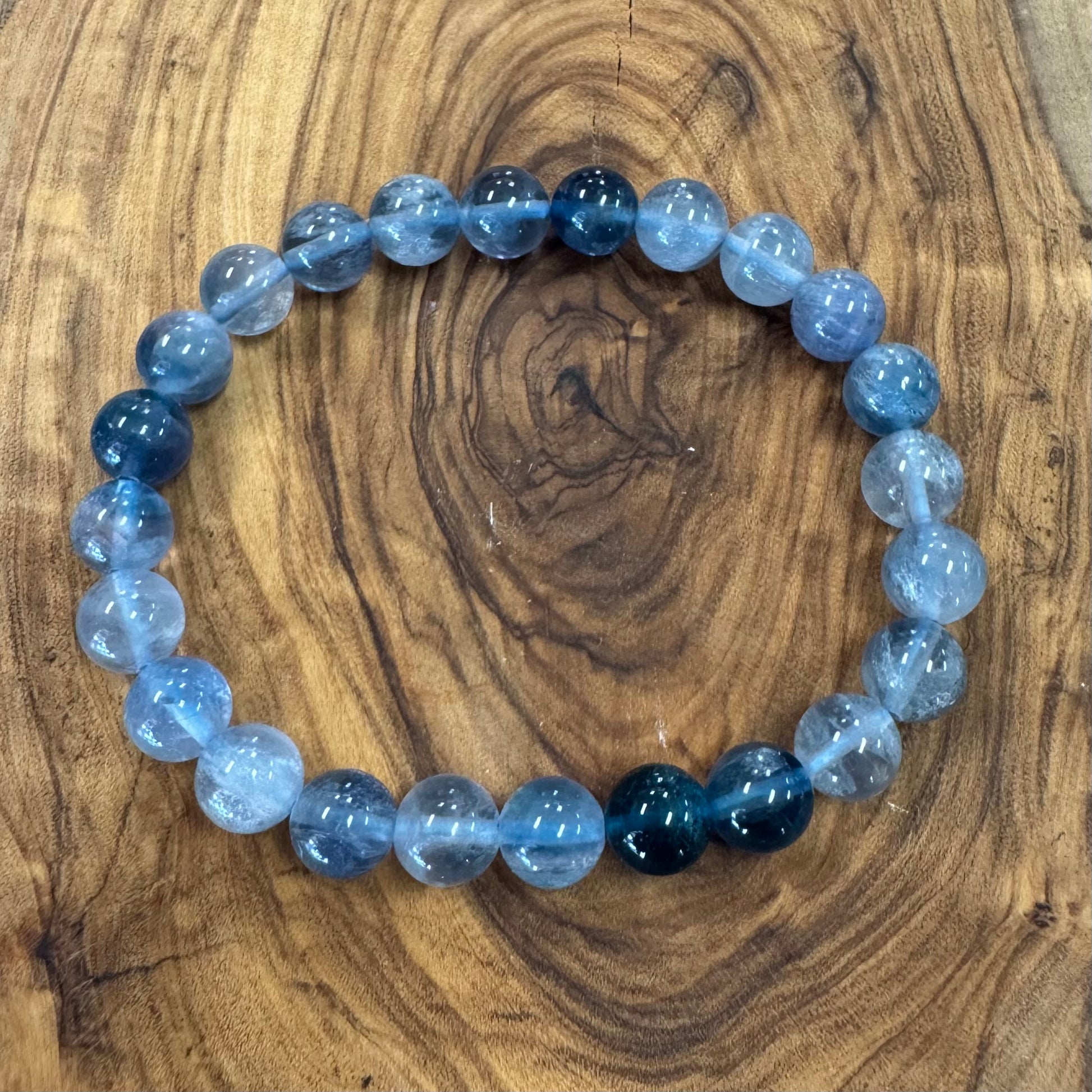 Beaded bracelet with blue and gray beads on a wooden surface