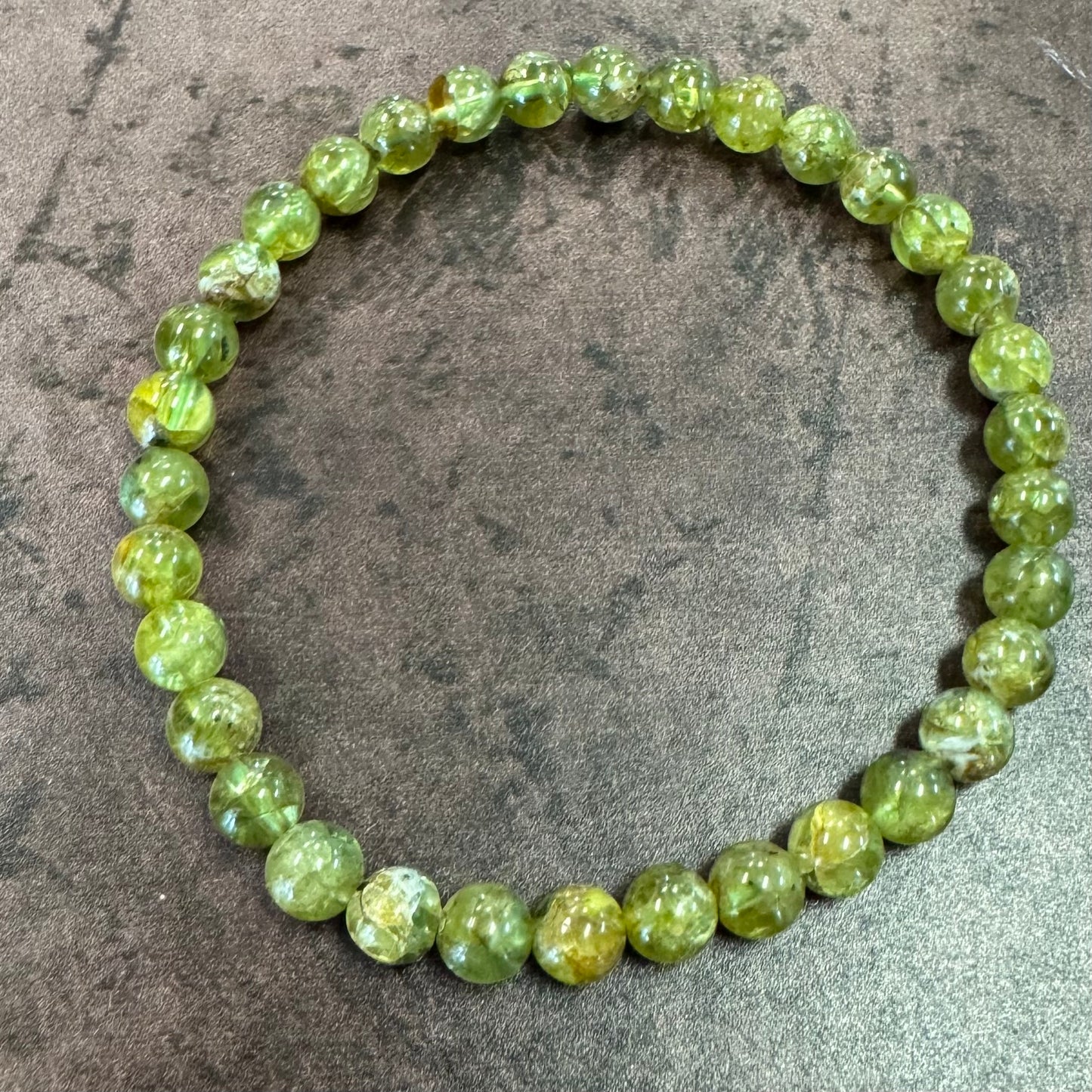 Green beaded bracelet on a textured gray surface