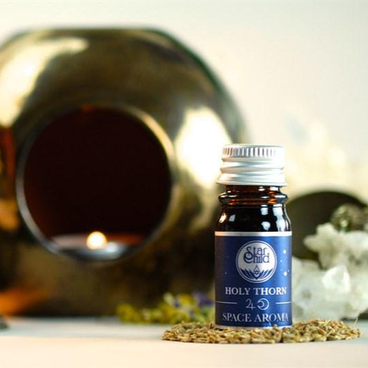 Bottle of 'Holy Thorn' space aroma with a blurred background featuring a metallic object and flowers.