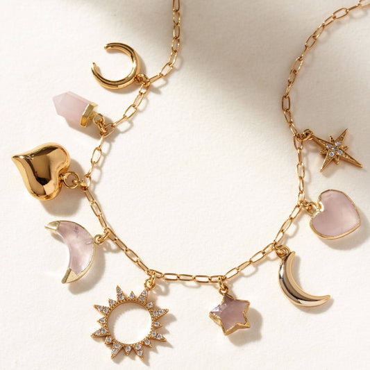 Gold necklace with various charms on a light background