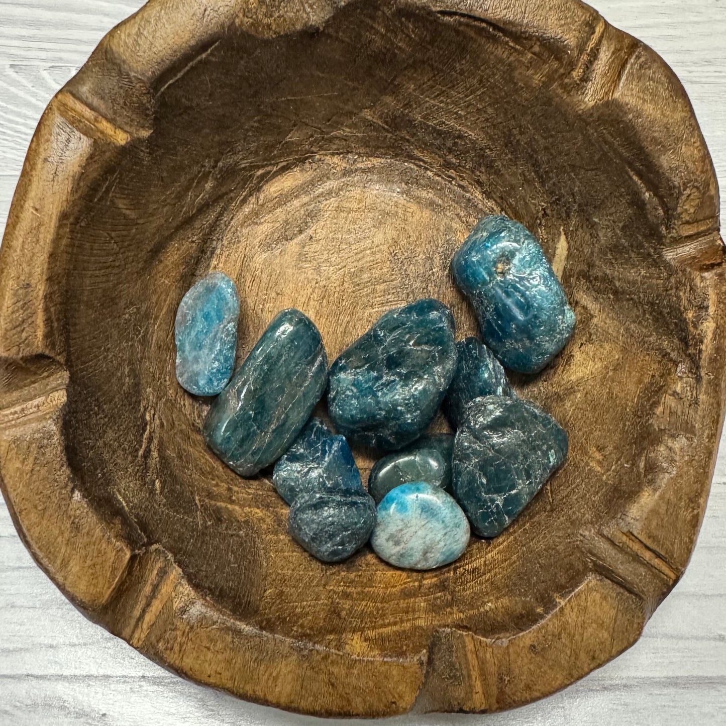 Wooden bowl with blue stones on a light wooden surface
