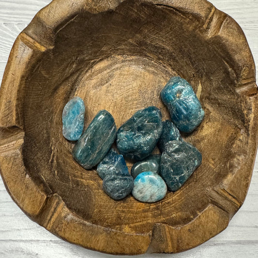 Wooden bowl with blue stones on a light wooden surface