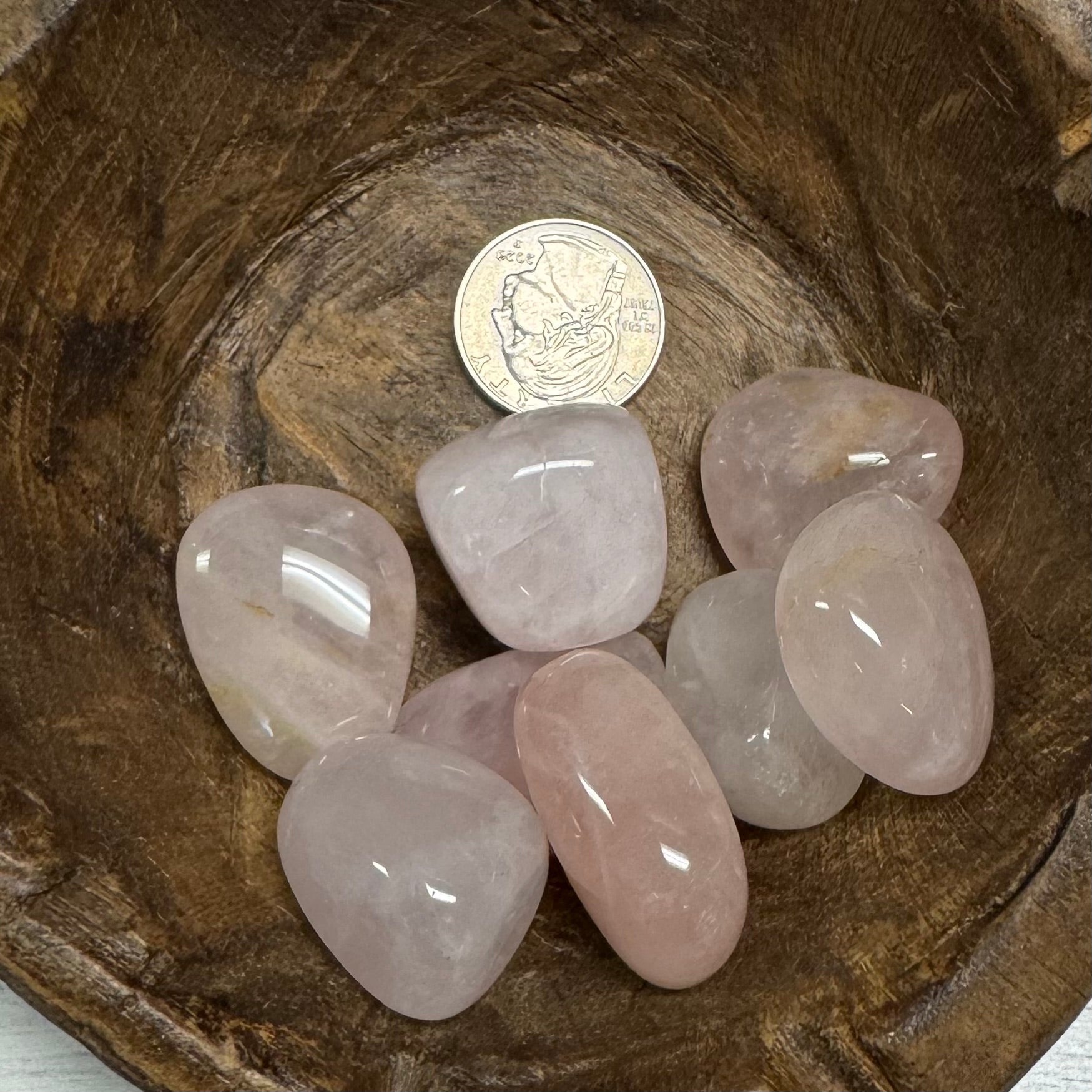 Pink crystals on a wooden surface with a coin for scale