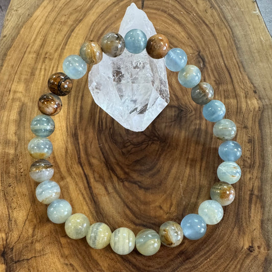 Beaded bracelet with multicolored beads on a wooden surface with a crystal.