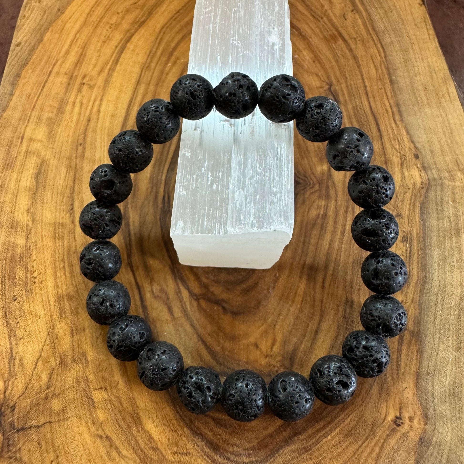 Black beaded bracelet on a wooden surface with a crystal