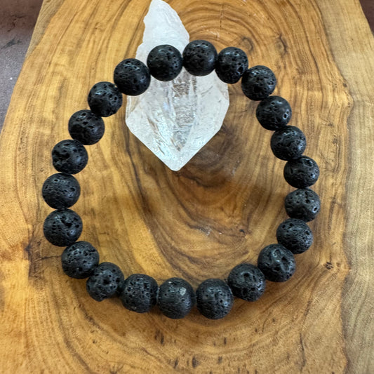 Black beaded bracelet on a wooden surface with a crystal