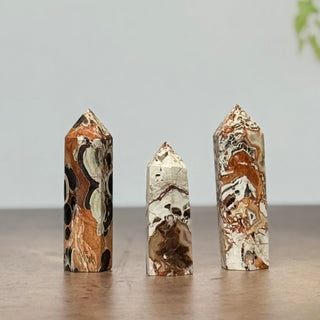 Three marbled stone pillars on a wooden surface with a neutral background