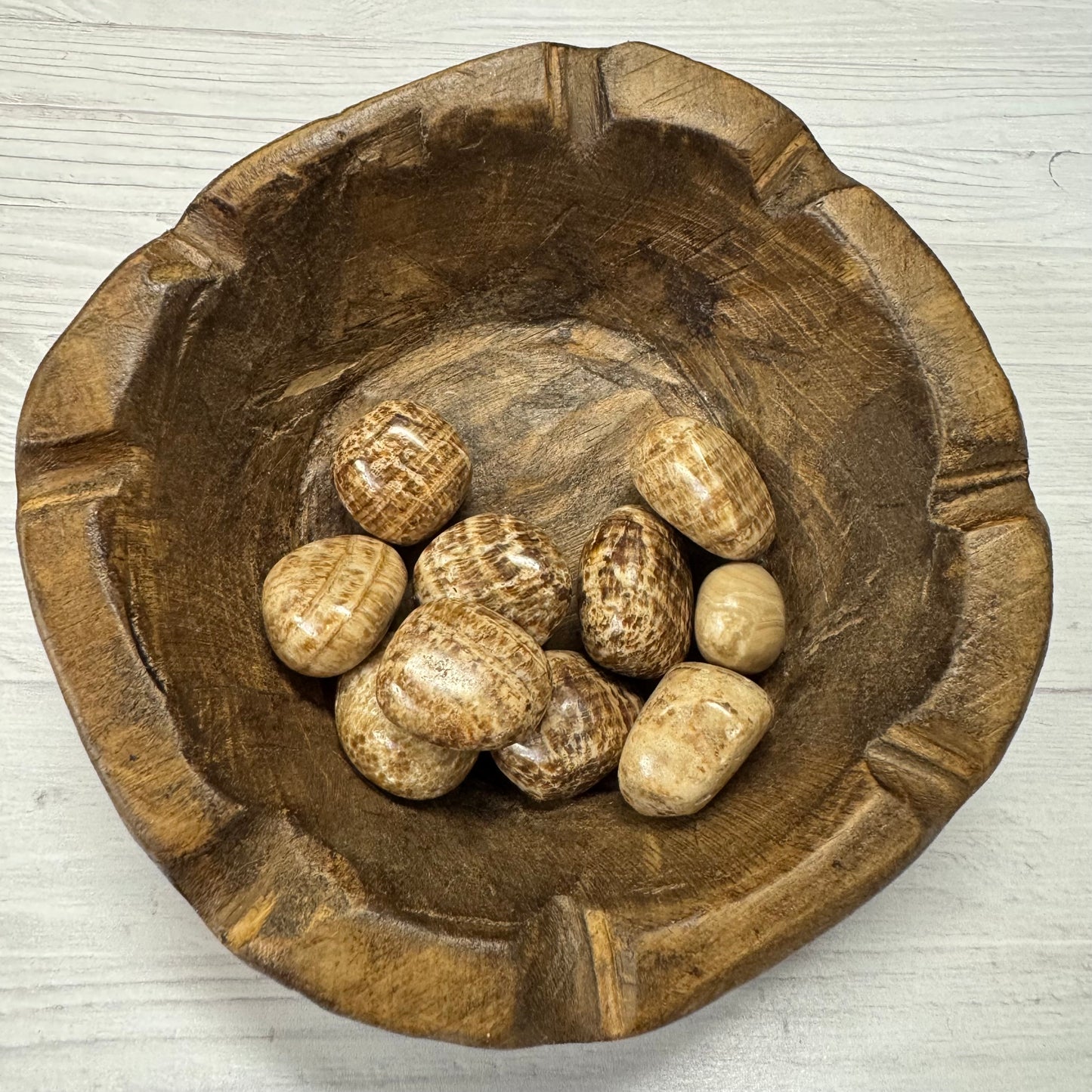 Wooden bowl with stones on a light wooden surface