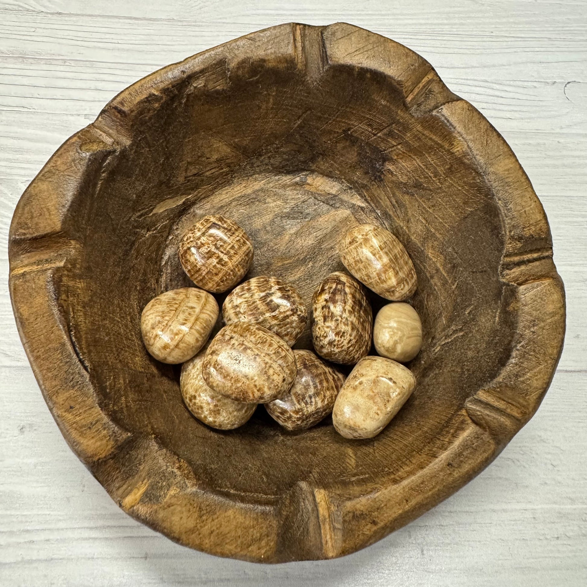 Wooden bowl with stones on a light wooden surface