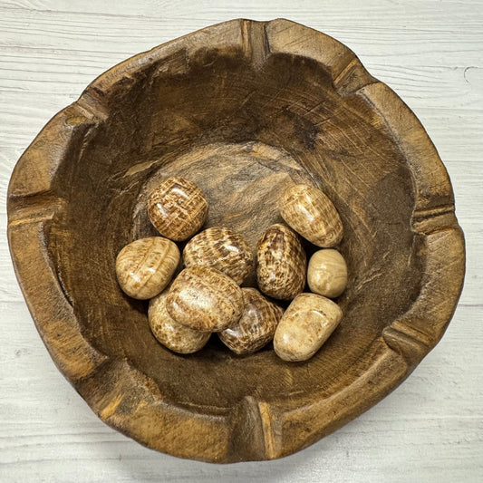 Wooden bowl with stones on a light wooden surface