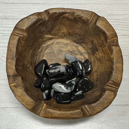 Wooden bowl with black stones on a light wooden surface