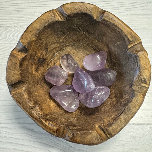 Wooden bowl with purple crystals on a white background