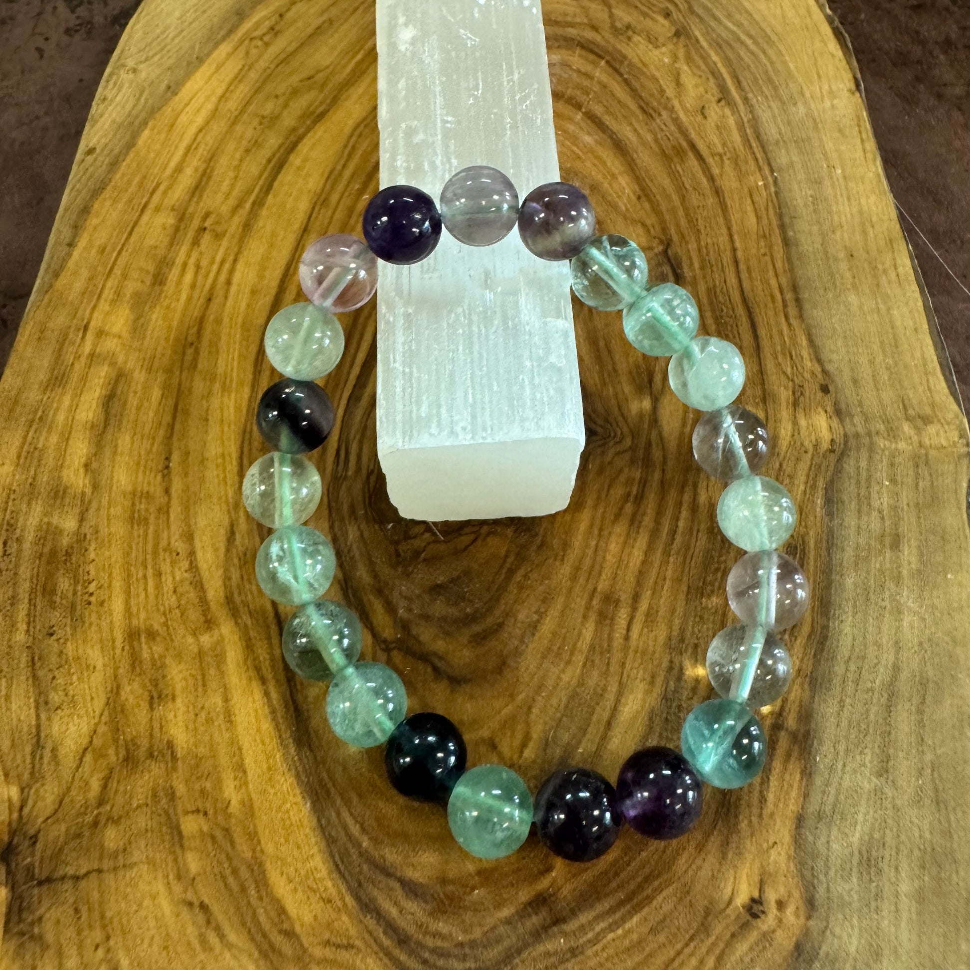 Multicolored beaded bracelet on a wooden surface with a crystal in the background