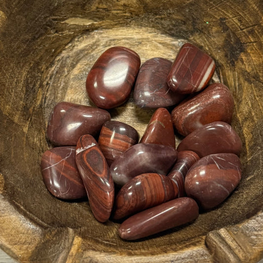 Polished red stones in a wooden bowl