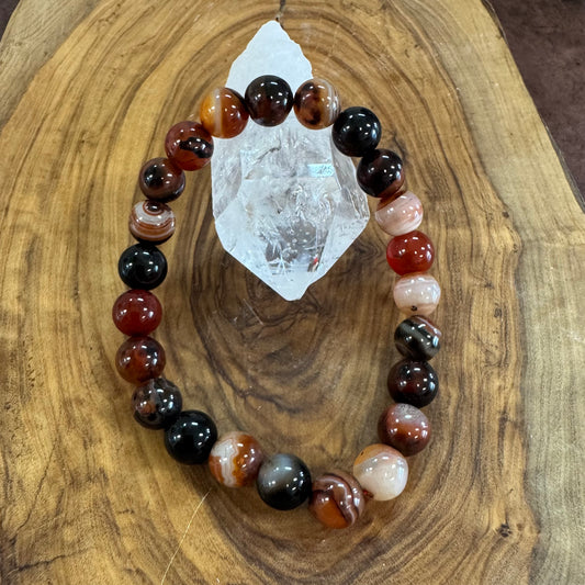 Multicolored beaded bracelet on a wooden surface with a crystal