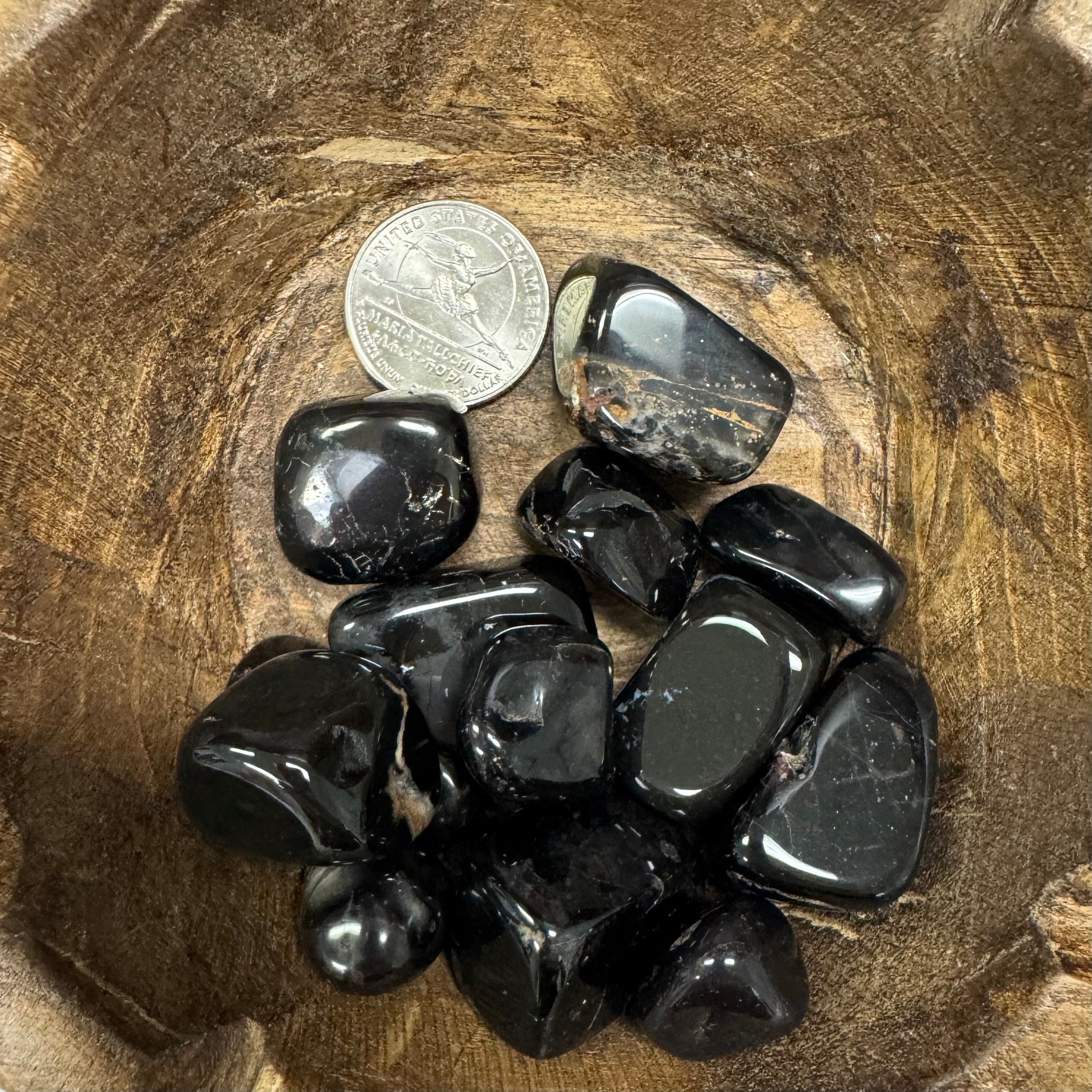 Black stones on a wooden surface with a coin for scale