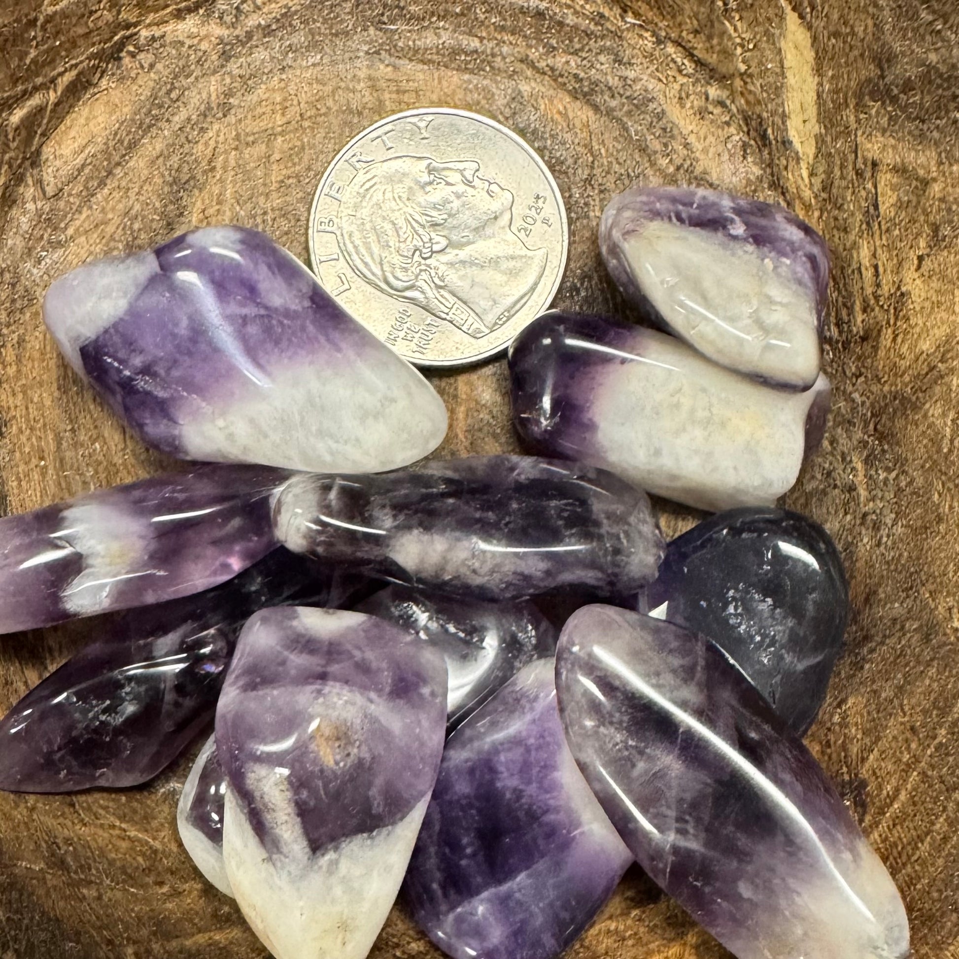 Amethyst crystals with a coin for scale on a wooden surface